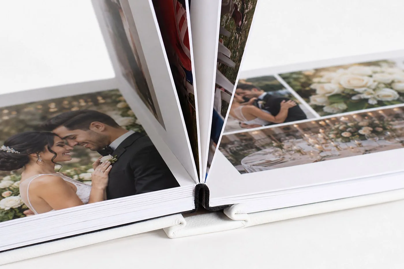 Un álbum LayFlat abierto sobre una mesa clara, con la fotografía de una boda cruzando el lomo sin corte